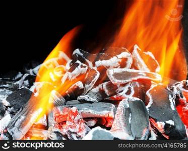 Burning wood embers with orange flames.
