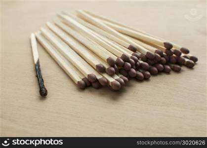 Burnt and whole head long wooden safety matchsticks on wooden background