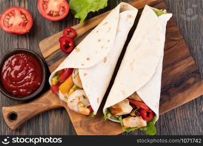 burrito with vegetables and tortilla on a wooden table. burrito with vegetables and tortilla