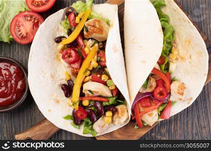 burrito with vegetables and tortilla on a wooden table. burrito with vegetables and tortilla
