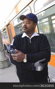 Bus driver holding mobile phone by bus