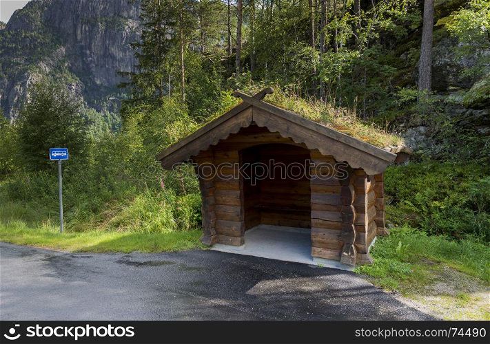 Bus stop on the side of the road on the country side in norway. The Majestic mountains landscape, fjord in Norway with wooden bus stop. traditional wooden bus stop with grass covered roof,. traditional bus stop in Norway