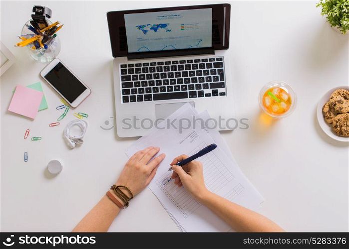 business, accounting and freelance concept - hands with papers and laptop computer working at office table. hands with papers and laptop at office table