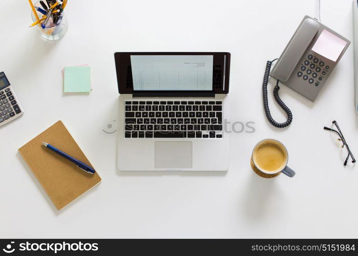 business, accounting and technology concept - laptop computer, phone and other office stuff on table top view. laptop, phone and other office stuff on table