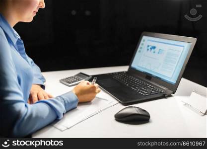 business, accounting, deadline and overwork concept - close up of businesswoman with tax form, laptop computer and calculator working at night office. businesswoman with papers working at night office