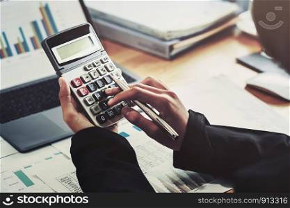 business accounting finance concept. accountant using calculator for calculate with laptop working in office