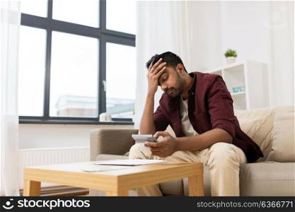 business, accounting, finances and people concept - upset man with papers and calculator at home. upset man with papers and calculator at home