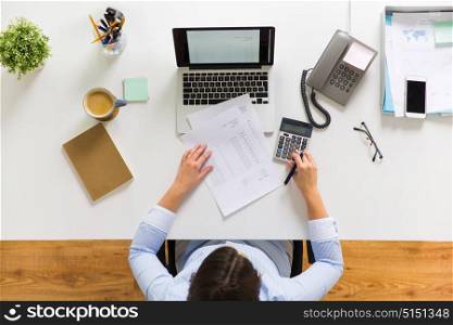 business, accounting, people and technology concept - businesswoman with laptop computer, calculator and papers working at office. businesswoman with tax report at office