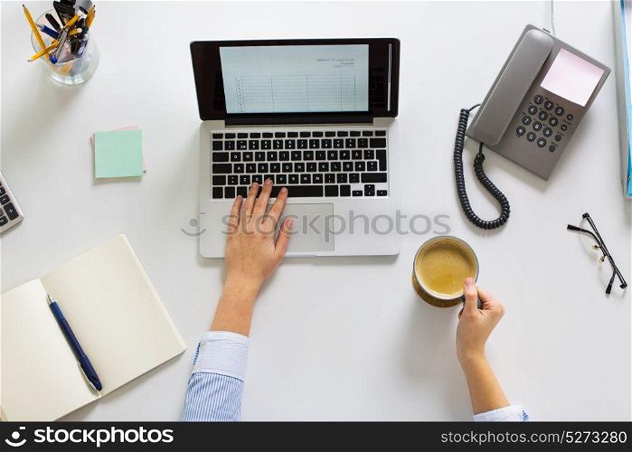 business, accounting, people and technology concept - hands of businesswoman with laptop computer working at office and drinking coffee. businesswoman with laptop and coffee at office