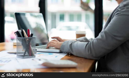 Business analyst concept the female officer typing financial information on the computer laptop.