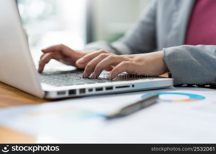 Business analyst concept the female officer typing financial information on the computer laptop.