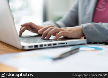 Business analyst concept the female officer typing financial information on the computer laptop.