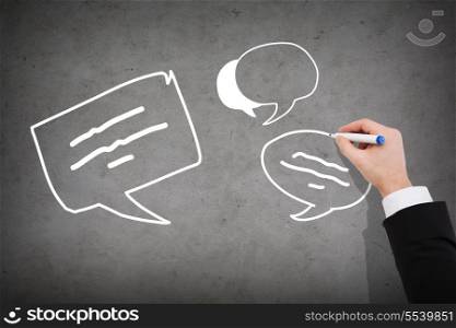 business and communication concept - close up of businessman drawing message bubbles on concrete wall
