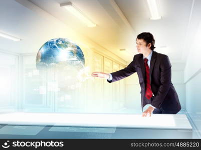 Business and communication innovations. Image of young businessman clicking icon on high-tech picture of globe