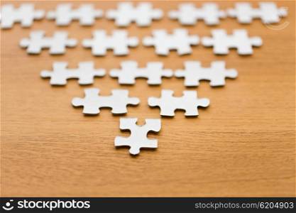business and connection concept - close up of puzzle pieces in pyramid shape on wooden surface. close up of puzzle pieces on wooden surface