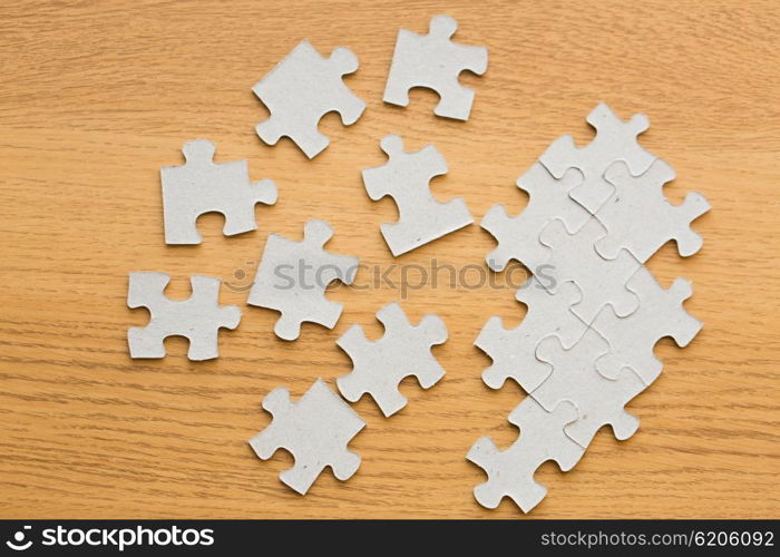 business and connection concept - close up of puzzle pieces on wooden surface. close up of puzzle pieces on wooden surface