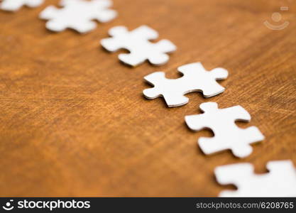 business and connection concept - close up of puzzle pieces on wooden surface. close up of puzzle pieces on wooden surface