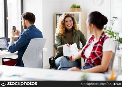business and creative people concept - female office workers giving each other papers. female office workers giving each other papers. female office workers giving each other papers