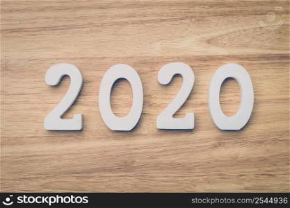 Business and design concept - wooden number 2020 for Happy new year text on wood table.