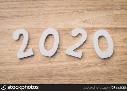 Business and design concept - wooden number 2020 for Happy new year text on wood table.
