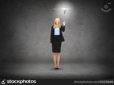 business and education concept - attractive young businesswoman with her finger up and light bulb