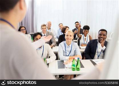 business and education concept - businesswoman or lecturer talking to group of people at conference, presentation or lecture. group of people at business conference or lecture