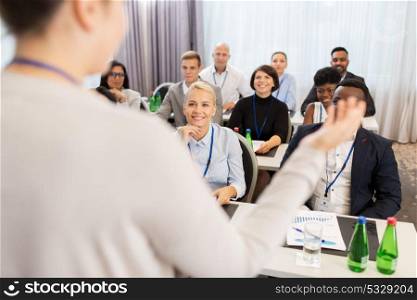 business and education concept - businesswoman or lecturer talking to group of people at conference or lecture. group of people at business conference or lecture