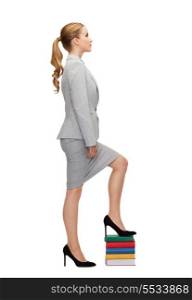 business and education concept - businesswoman stepping on pile of books