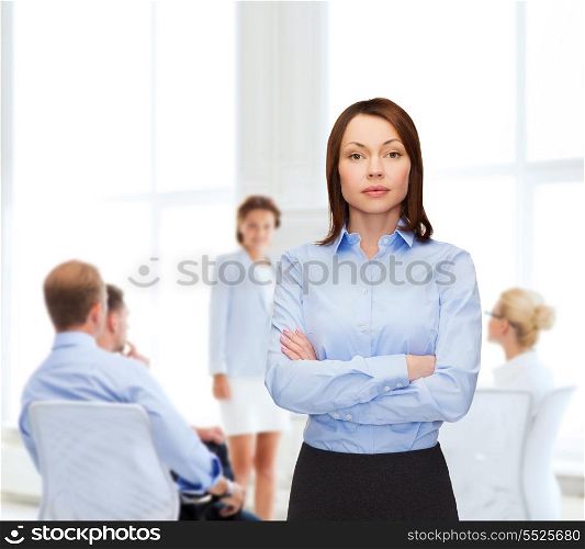business and education concept - friendly young businesswoman with crossed arms at office