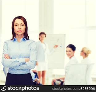 business and education concept - friendly young businesswoman with crossed arms at office. smiling businesswoman with crossed arms at office