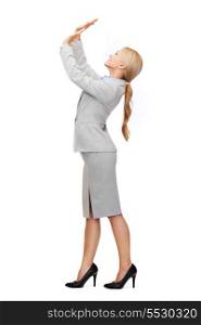 business and education concept - friendly young smiling businesswoman pushing up something imaginary