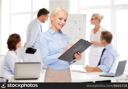 business and education concept - friendly young smiling businesswoman with clipboard and pen