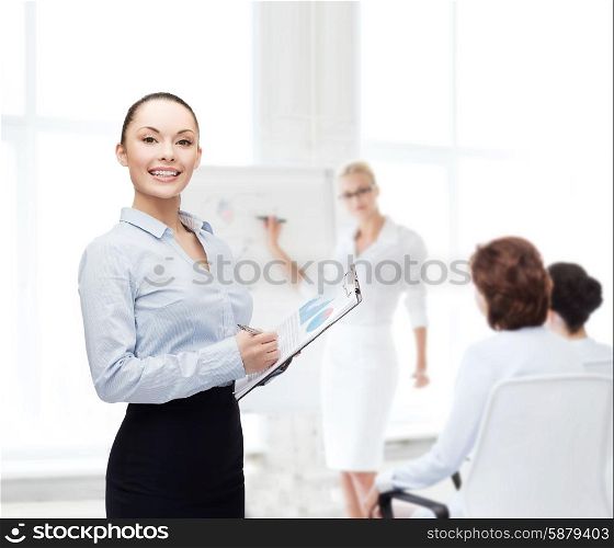 business and education concept - friendly young smiling businesswoman with clipboard and pen. young smiling businesswoman with clipboard and pen
