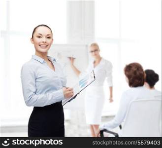 business and education concept - friendly young smiling businesswoman with clipboard and pen. young smiling businesswoman with clipboard and pen