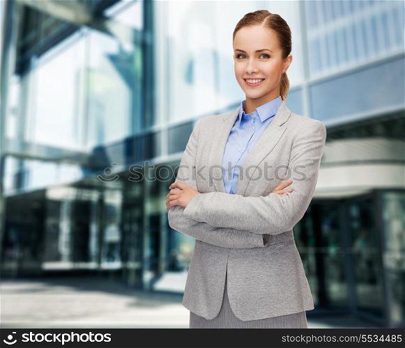 business and education concept - friendly young smiling businesswoman with crossed arms
