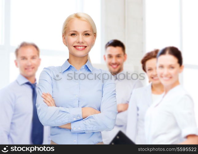 business and education concept - friendly young smiling businesswoman with crossed arms