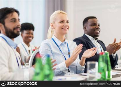 business and education concept - group of happy people applauding at international conference. people applauding at business conference