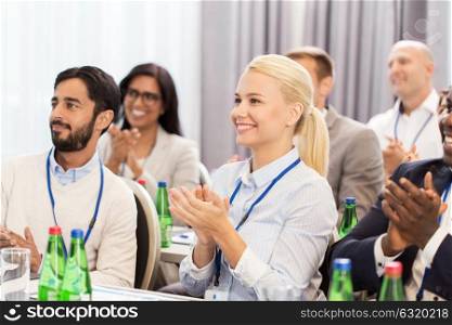 business and education concept - group of happy people applauding at international conference. people applauding at business conference