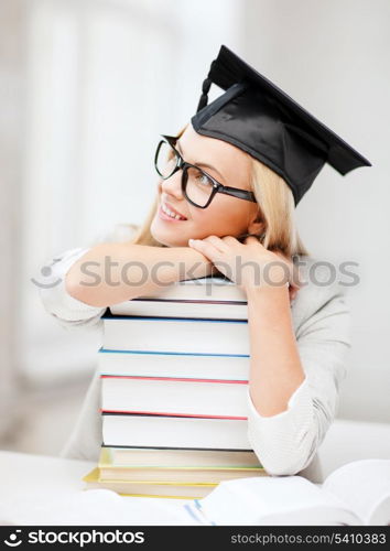 business and education concept - happy student in graduation cap with stack of books