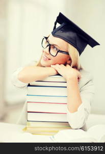 business and education concept - happy student in graduation cap with stack of books. student in graduation cap