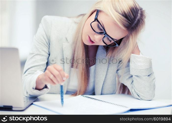 business and education concept - indoor picture of bored and tired woman taking notes. bored and tired woman