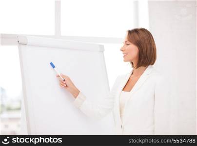 business and education concept - smiling businesswoman pointing to flipchart