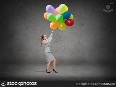 business and education concept - smiling businesswoman pulling down bunch of balloons
