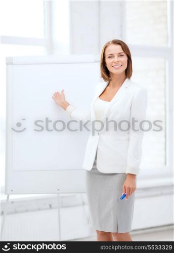 business and education concept - smiling businesswoman showing flipchart