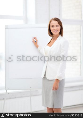 business and education concept - smiling businesswoman writing on flipchart
