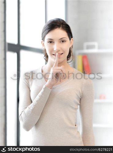 business and education concept - young woman with finger on lips