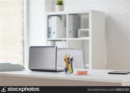 business and interior concept - laptop with pen and stickers on office table. laptop with pen and stickers on office table