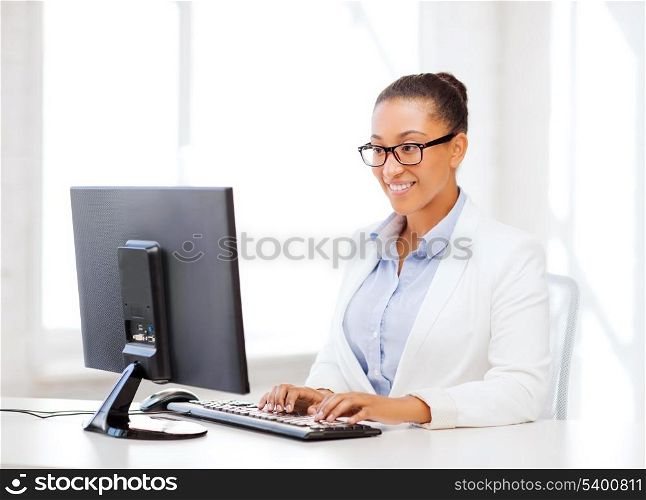 business and internet concept - smiling african businesswoman with computer in office