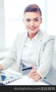 business and internet concept - smiling businesswoman with laptop using credit card. businesswoman with laptop using credit card
