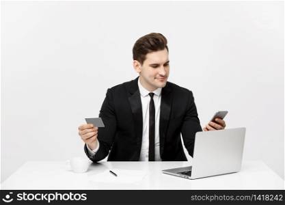 Business and Lifestyle Concept: Portrait smiling businessman sitting in office and shopping online pays by credit card with labtop.. Business and Lifestyle Concept: Portrait smiling businessman sitting in office and shopping online pays by credit card with labtop